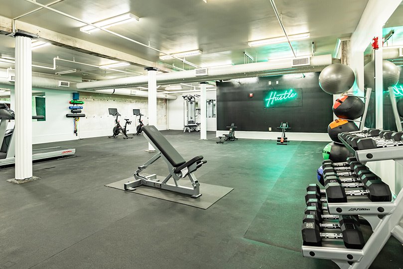 Fitness Center at Dannenberg Lofts with benches, dumbbells, and cardio equipment